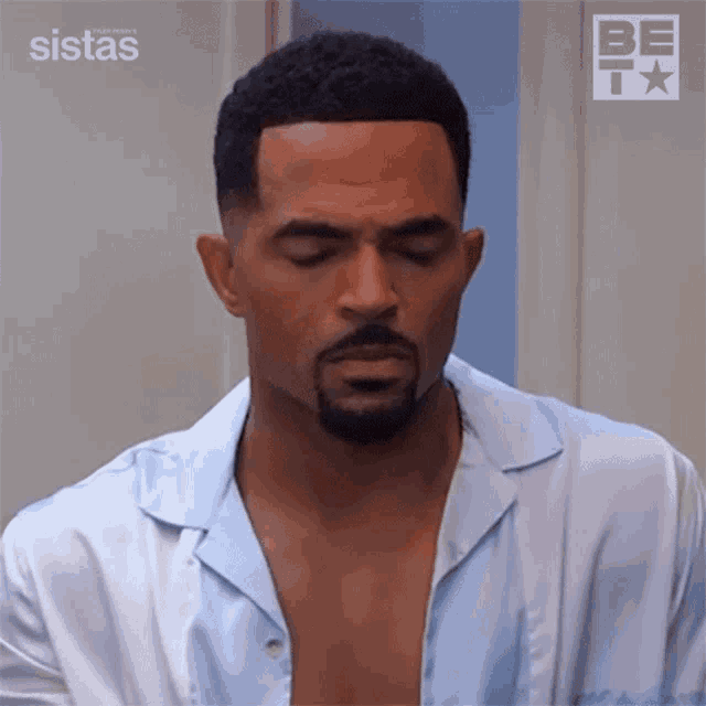a man with a beard is wearing a blue shirt with his shirt open .