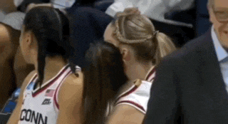 a woman in a conn jersey is kissing another woman .