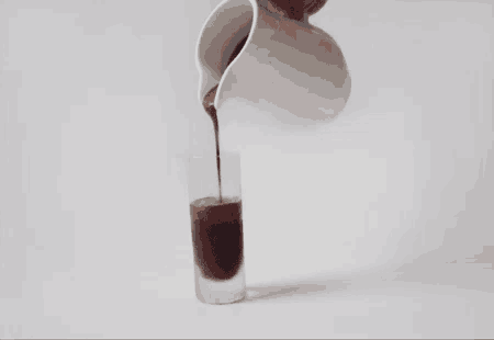a glass of liquid is being poured from a pitcher into a glass