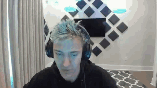 a man wearing headphones is sitting in front of a computer screen in a living room .