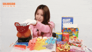 a woman is holding a giant gummy bear in front of a box of giant gummy candy