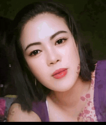 a close up of a woman 's face wearing a purple shirt