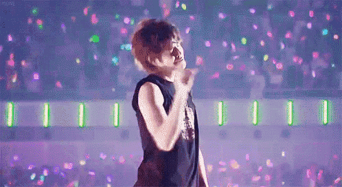 a man is standing on a stage in front of a crowd and giving a peace sign .