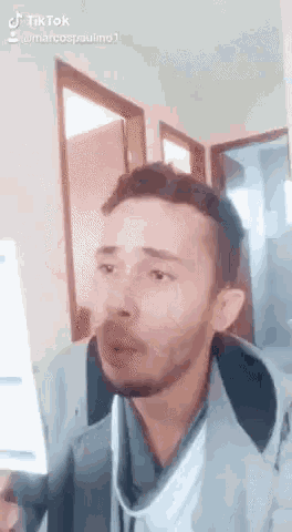 a man with a beard is holding a piece of paper in his hand and making a funny face .