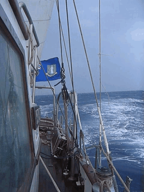 a blue flag with a shield on it is hanging from the side of a boat in the ocean