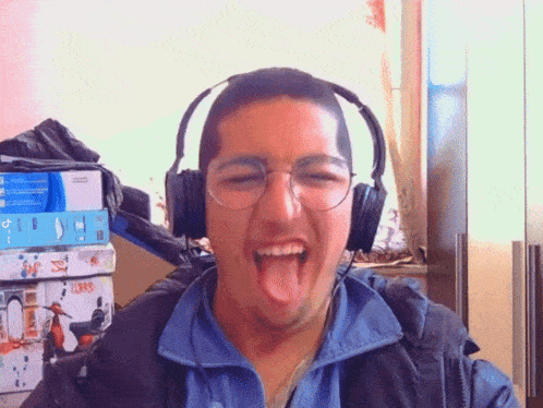 a man wearing headphones and glasses sticks out his tongue