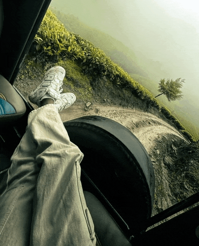 a person sitting in a car with their feet on a tire looking out the window