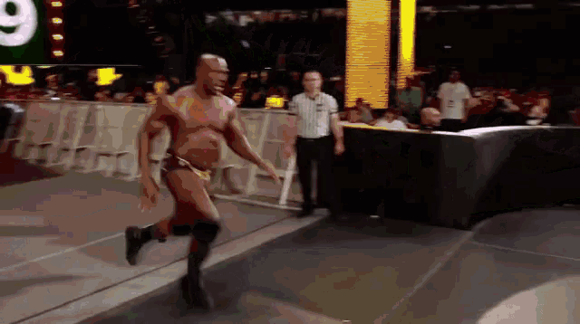 a man in a wrestling ring with a referee and a sign that says 9