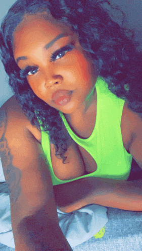 a woman in a neon green tank top is laying down