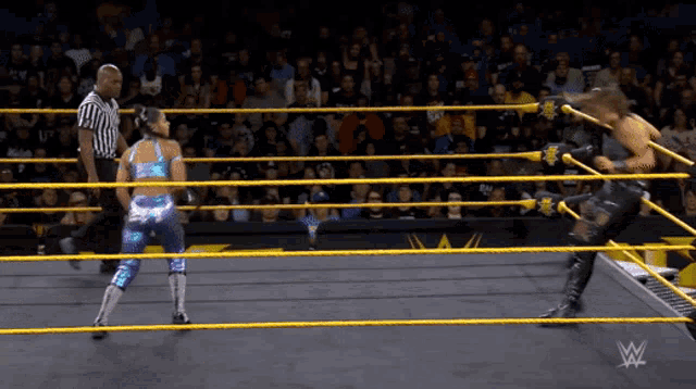 two women are wrestling in a wrestling ring with a referee watching