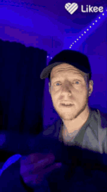 a man with blue eyes is taking a selfie with a likee heart in the corner