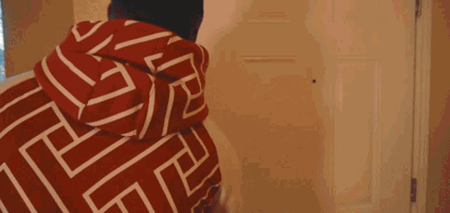 a man wearing a red and white hoodie with a greek key pattern