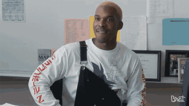 a man wearing a white shirt that says brat on the sleeve