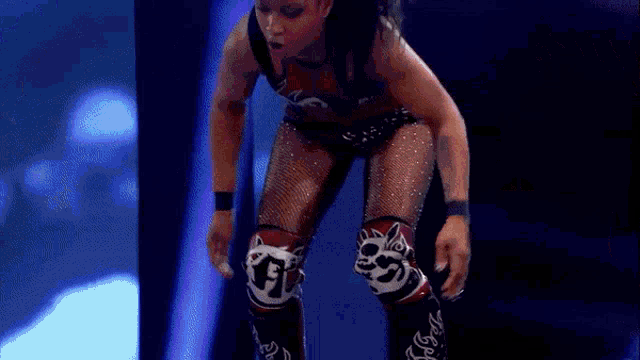 a woman is laying on the ground in a wrestling ring while a referee stands behind her