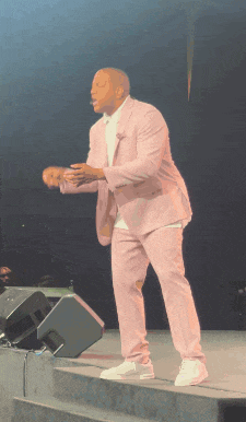 a man in a pink suit is standing on stage