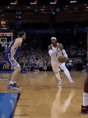 a basketball player is dribbling the ball while another player tries to stop him