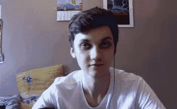 a young man wearing headphones and a white shirt is sitting in front of a wall .