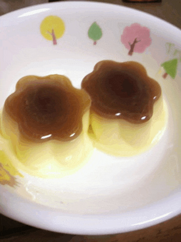 two desserts on a plate with trees and flowers on it
