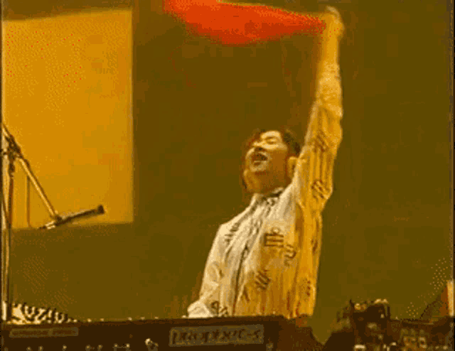 a man is playing a keyboard and holding a red flag in the air
