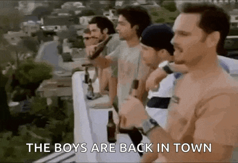 a group of men are standing next to each other on a balcony drinking beer .