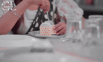 a woman is cutting a piece of cake on a plate with cl written on the bottom right