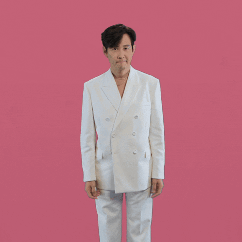 a man in a white suit with his arms outstretched on a pink background