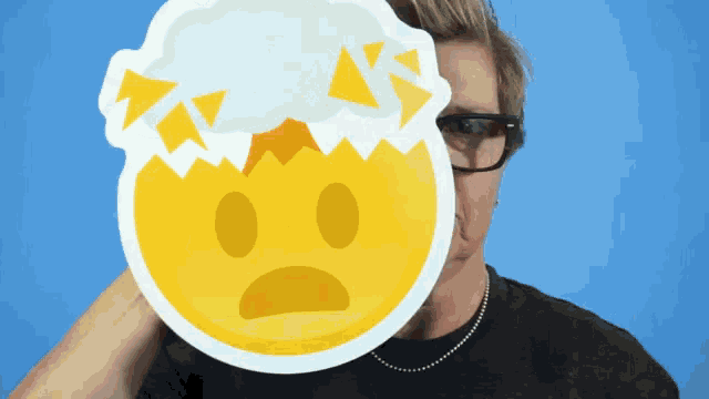 a man covering his face with a sticker that looks like a smiley face with a cloud on it