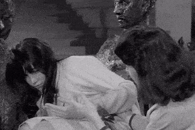 a black and white photo of two women sitting next to a statue of a man .