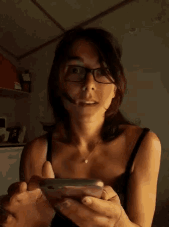 a woman wearing glasses is holding a cell phone