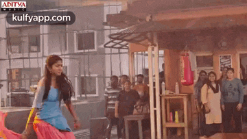 a woman is dancing in front of a crowd of people .