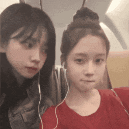 two girls wearing headphones are sitting next to each other on a plane