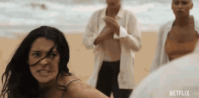 a group of people are standing on a beach . one of the women is making a funny face .
