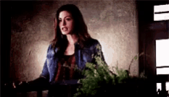 a woman in a denim jacket is standing in front of a window .