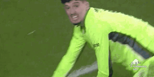a soccer player wearing a green jersey is kneeling on the field .