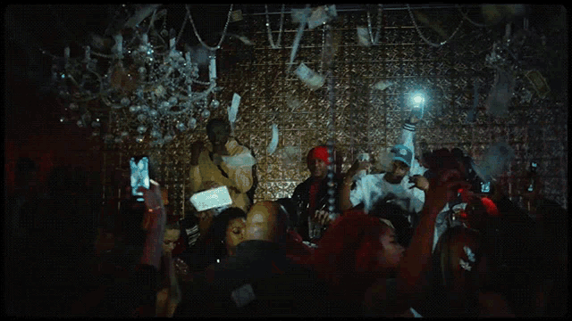 a crowd of people at a party with a man holding a bag of money in his hand