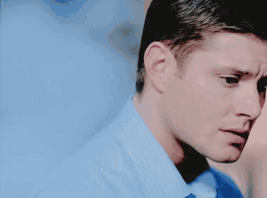 a close up of a man 's face with a blue shirt