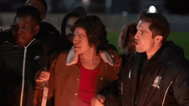a man in a nike jacket points to another man in a brown jacket