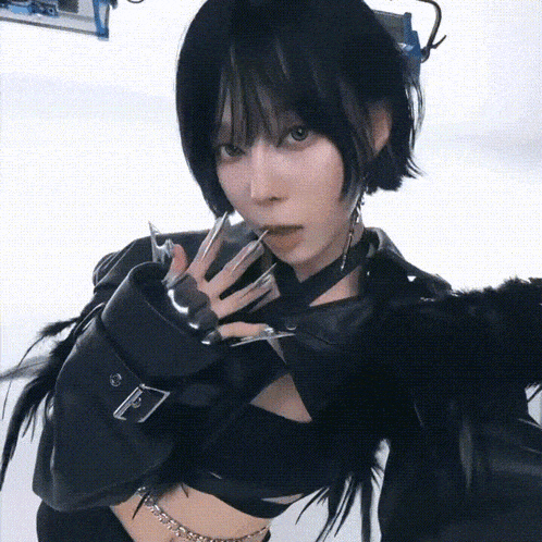 a woman with short black hair is wearing a black jacket and feathers on her arms .