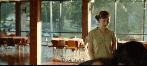 a woman standing in a room with tables and chairs says it 's on cunt