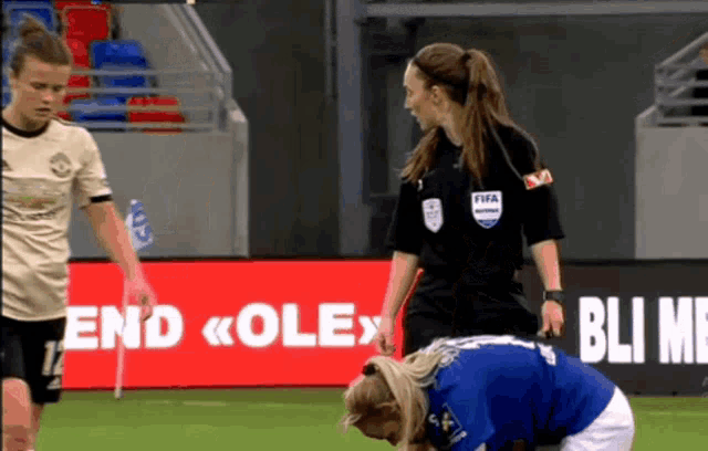 a female referee is standing next to a female soccer player