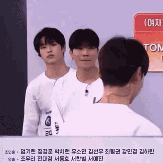 a group of young men standing next to each other in front of a sign that says tom