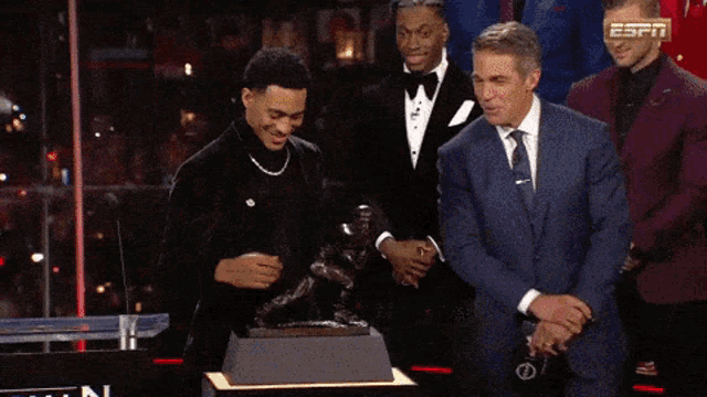 a group of men standing around a trophy with the espn logo visible