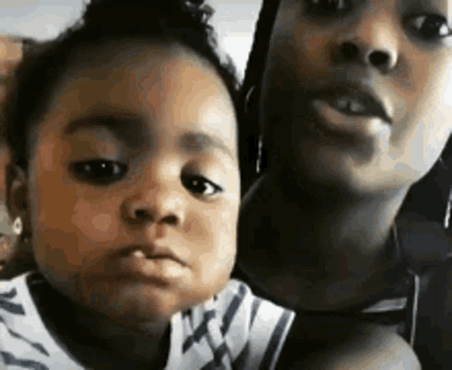 a woman is holding a little girl in her arms and they are looking at the camera .