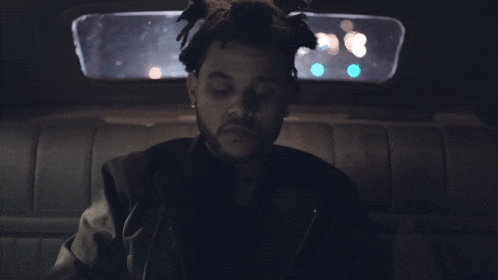 a man with dreadlocks is sitting in the back of a car with his eyes closed