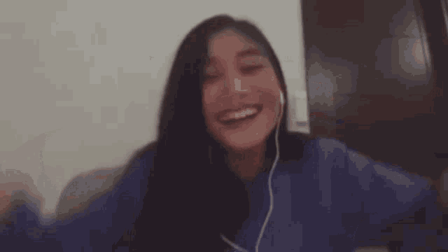 a woman wearing headphones is giving a peace sign while smiling .
