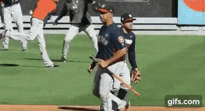 a baseball player is holding a bat while walking on the field .