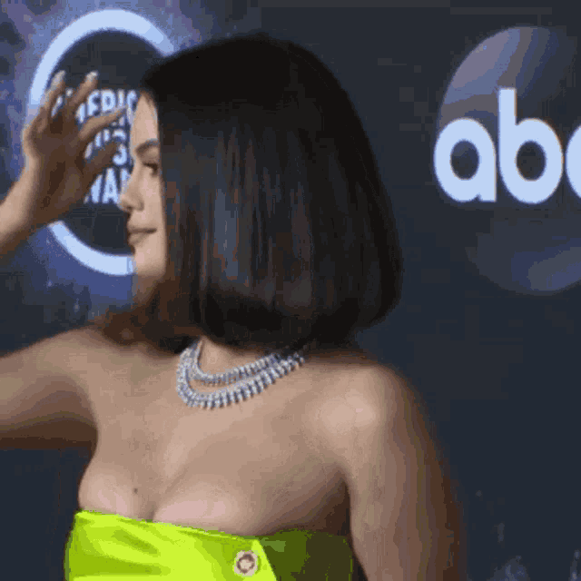 a woman in a yellow strapless dress stands in front of an abc logo