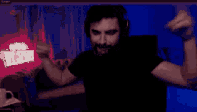 a man with a beard and headphones is dancing in front of a computer screen
