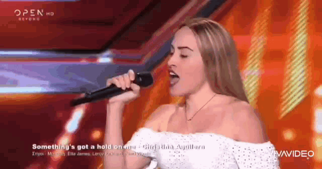 a woman is singing into a microphone on a stage