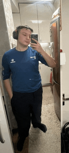 a young man is taking a selfie in front of a mirror in a kitchen .